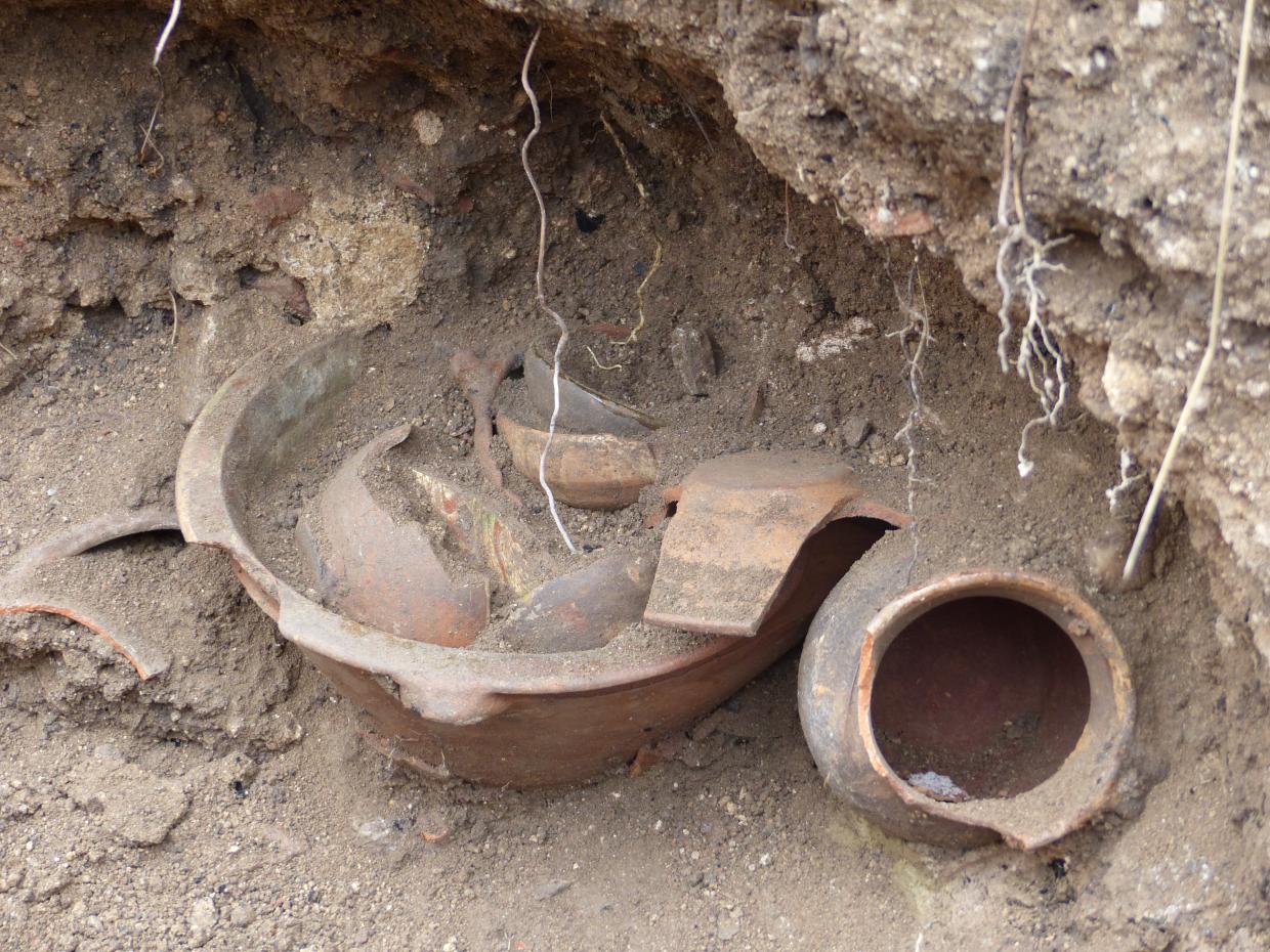 Assiettes, tasses et écuelles sont rangées à l’intérieur de la grande bassine en terre vernissée entourée par les coquemars et enterrées dans un jardin.